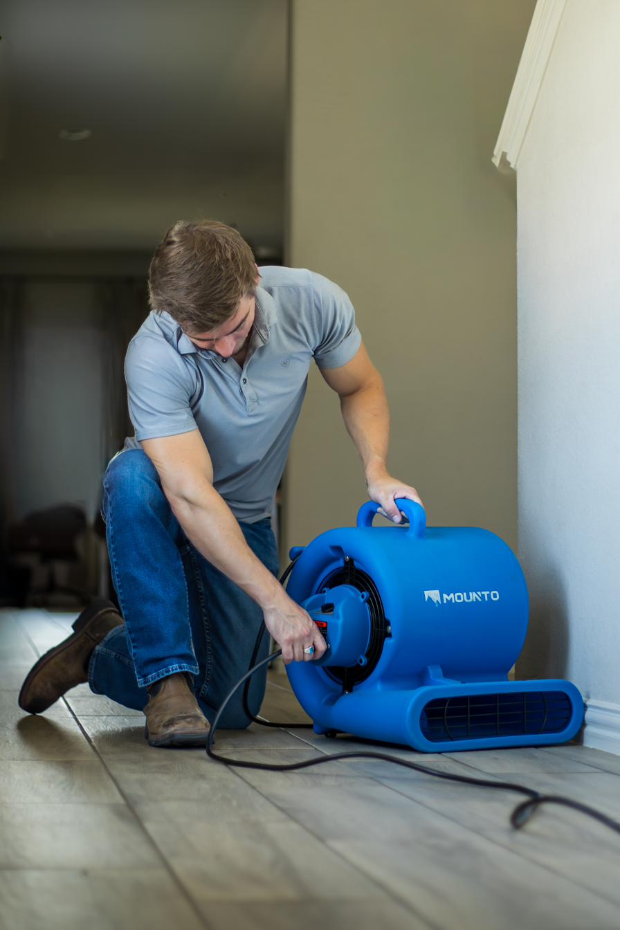 Josh Merlene carrying air movers into a job site